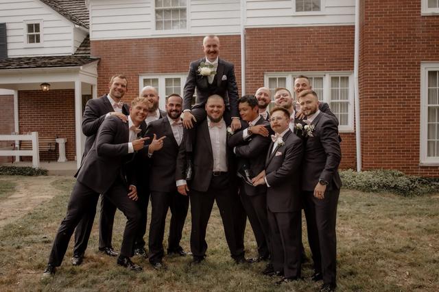 Groomsmen celebrating in front of the brick house