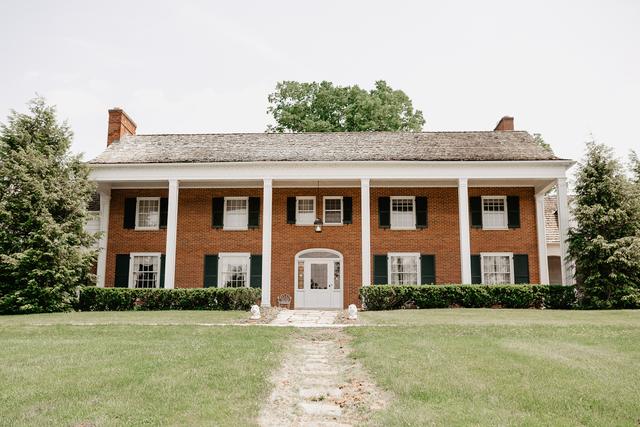 Front of the brick estate house with white columns
