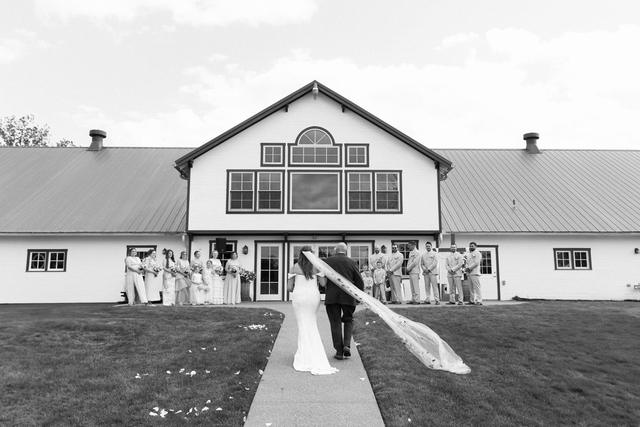 Bride's veil blowing on the walkway in front of the barn