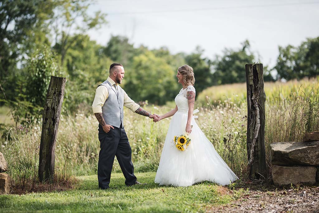 bride with sunflowers holdig grooms hand