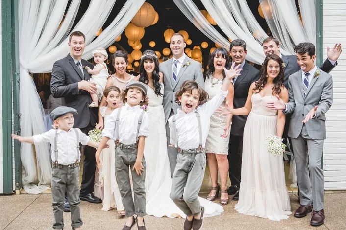 Wedding party and children jumping for joy inside the barn
