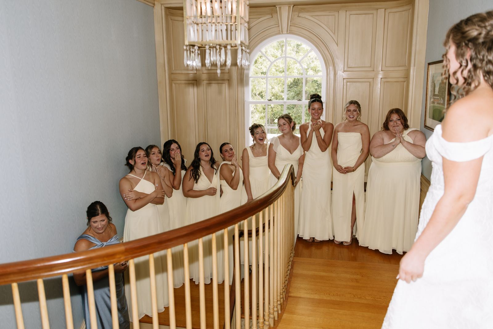 Bridesmaids reacting to the bride on the house staircase