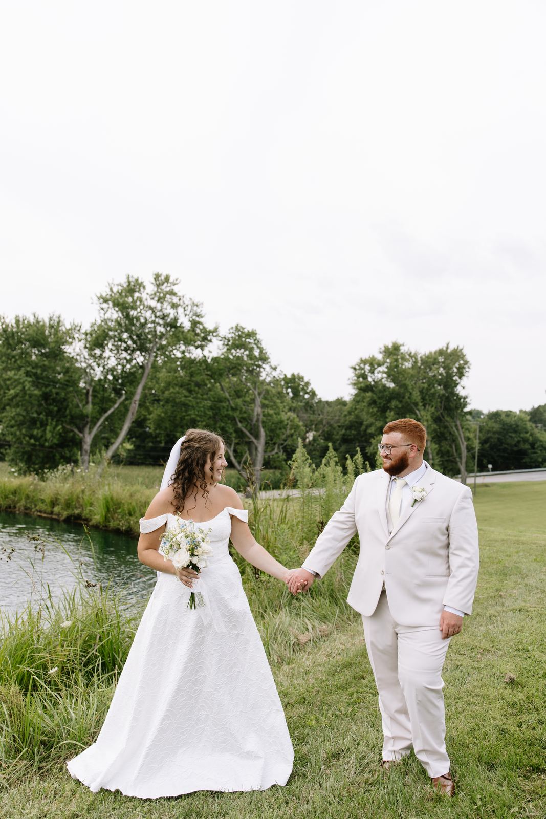 Bride and groom holding hands beside the pond
