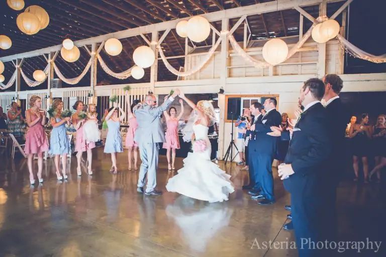 Bride and her father dancing as the wedding party cheers in the barn