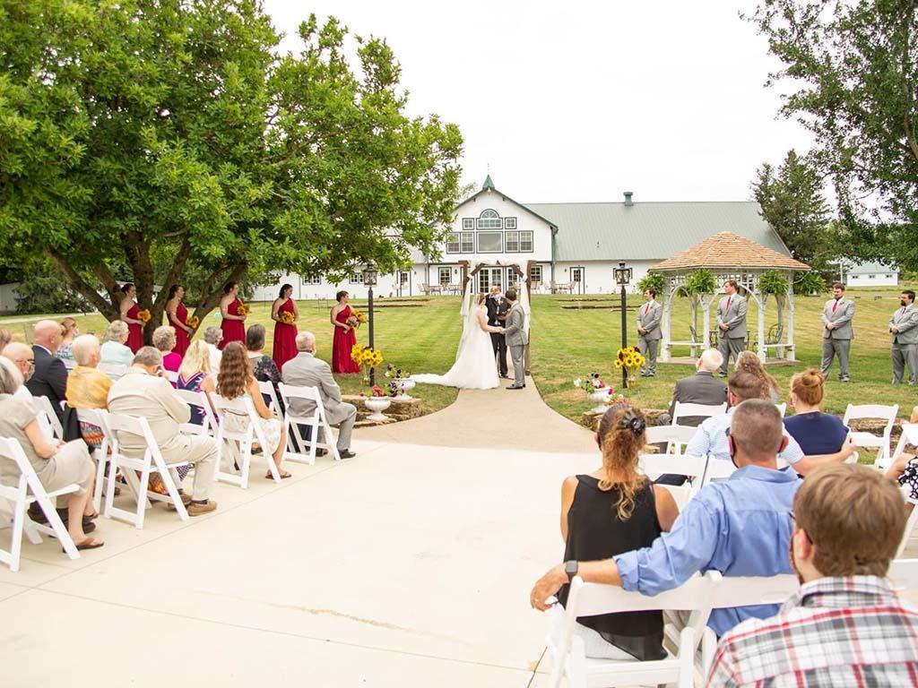 Ceremony on the lawn beside the white gazebo with the barn behind