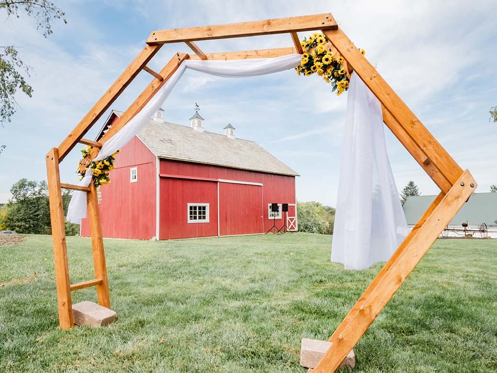 Wooden arch with sunflowers in front of the little red barn
